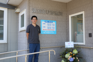 新しくなった看板の前に立つ田川医師