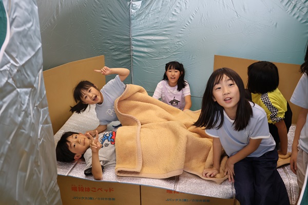 ダンボールベッドに寝る児童
