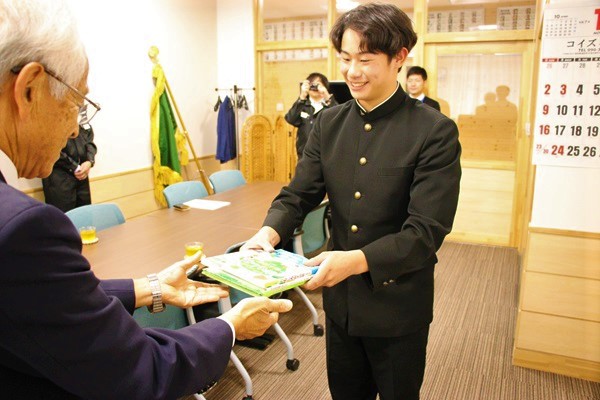 平井勝美組合長から本を受け取る佐藤太陽生徒会長