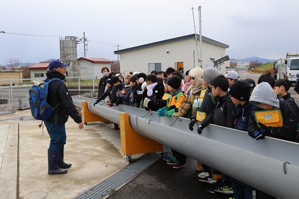 ふ化増殖施設の蓄養池で説明する絹張講師