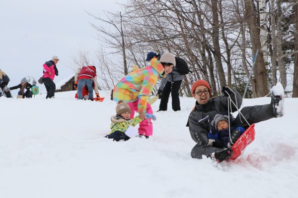 坂の上からそり滑りを楽しむ子どもたち
