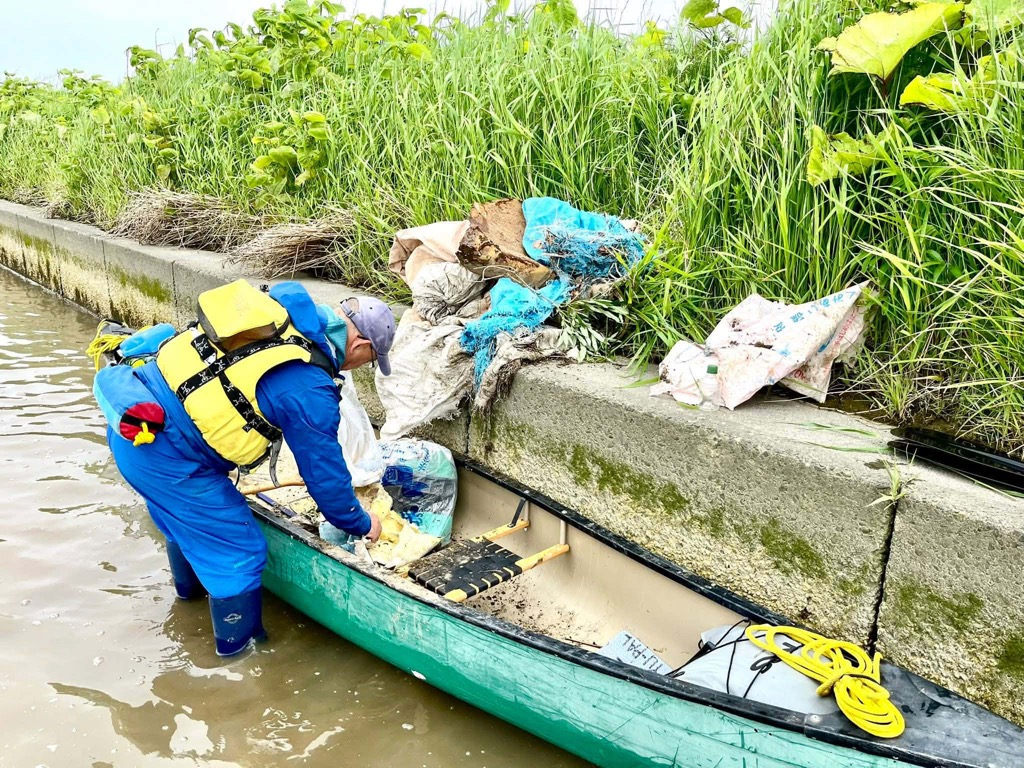 カヌーで川沿いのごみを拾う参加者