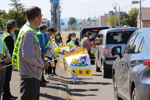 沿道で交通安全旗を振る参加者